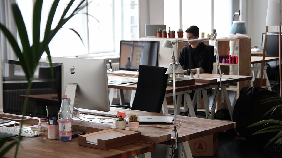 Модерно coworking пространство с работни места и служител на лаптоп